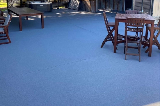 Spray on concrete resurfacing in blue color with standing furniture outside